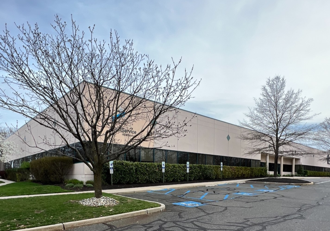 A building with trees and parking lot in front of it.