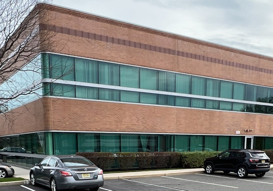 A building with two cars parked in front of it.