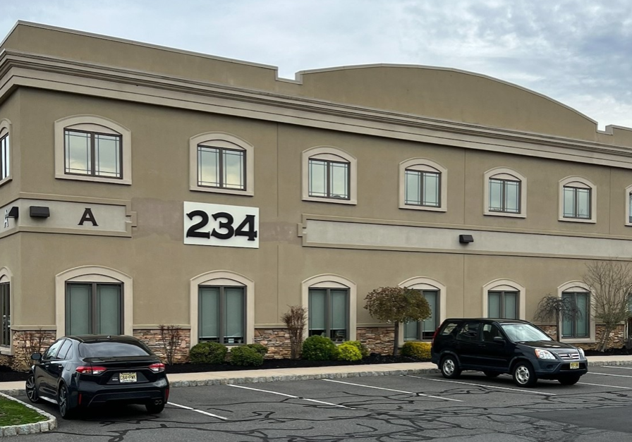 A building with two cars parked in front of it.