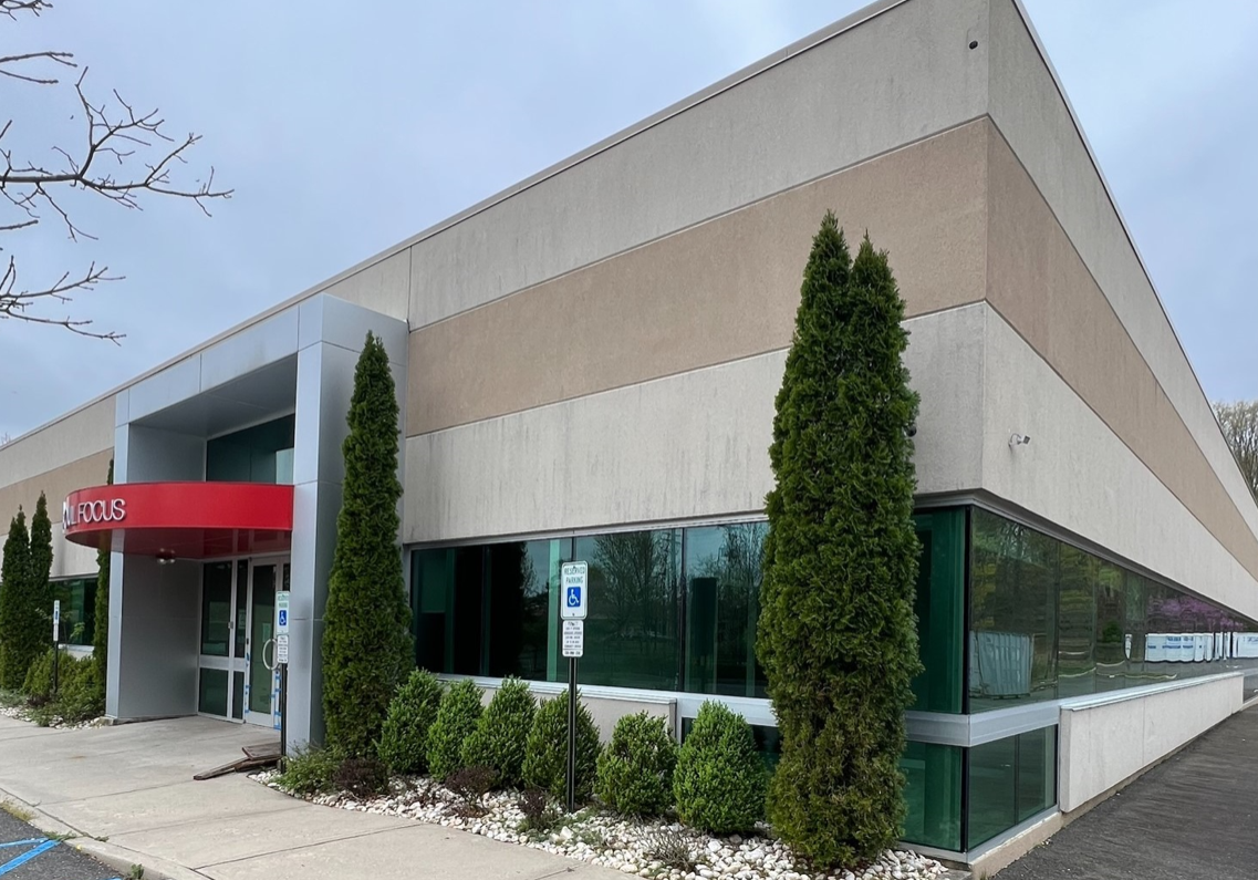 A building with a red awning and bushes in front of it.